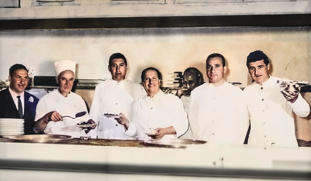 Historisches Foto einer Küchenbrigade in weißen Jacken an der Essensausgabe